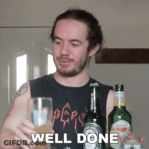 A Man In A Black Shirt Holds A Glass Of Beer In Front Of A Bottle Of Amstel Beer GIF