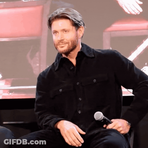 A Man In A Black Shirt Holds A Microphone In His Hand GIF