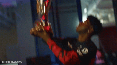 A Man In A Black Shirt Holds A Trophy In His Hand GIF