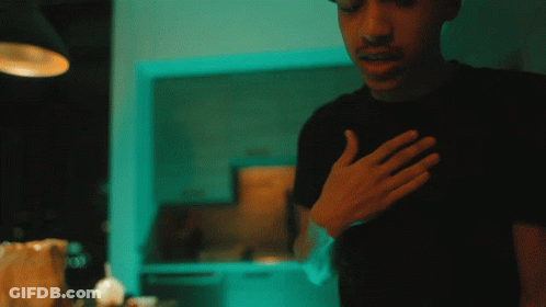 A Man In A Black Shirt Holds His Hand To His Heart GIF