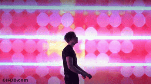 A Man In A Black Shirt Is Dancing In Front Of A Pink And Blue Background GIF