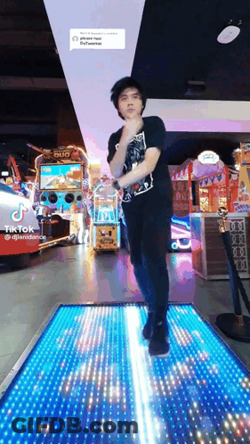 A Man In A Black Shirt Is Dancing On A Lighted Floor In An Amusement Park .. GIF