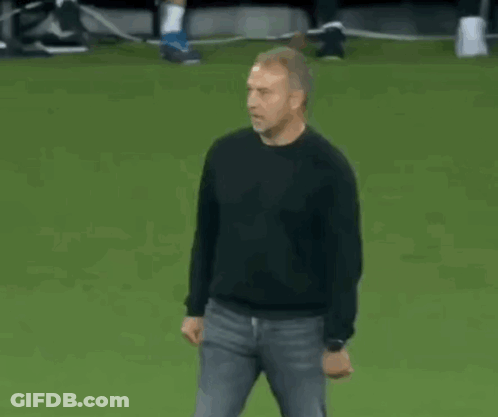 A Man In A Black Shirt Is Dancing On A Soccer Field . GIF
