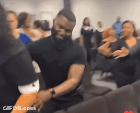 A Man In A Black Shirt Is Dancing With A Woman In A Crowd . GIF