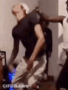 A Man In A Black Shirt Is Dancing With Another Man In A White Shirt In A Room . GIF