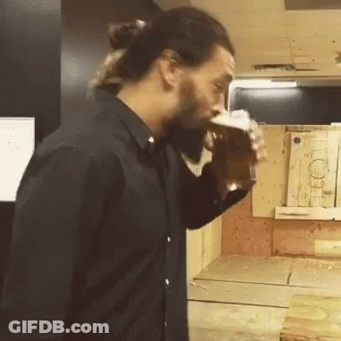 A Man In A Black Shirt Is Drinking A Beer From A Glass GIF