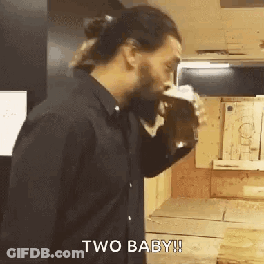 A Man In A Black Shirt Is Drinking A Beer From A Glass . GIF