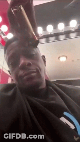 A Man In A Black Shirt Is Getting His Hair Cut GIF