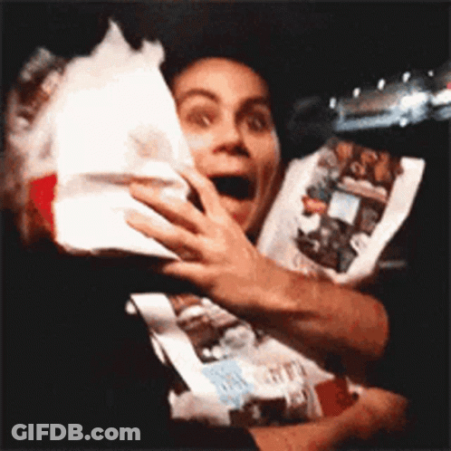 A Man In A Black Shirt Is Holding A Bag Of Food . GIF
