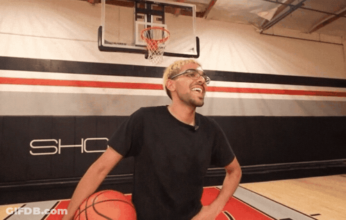 A Man In A Black Shirt Is Holding A Basketball In Front Of A Wall That Says Sho GIF