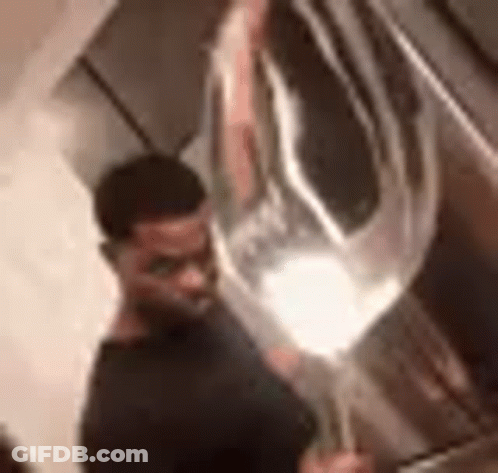 A Man In A Black Shirt Is Holding A Large Balloon In His Hand . GIF