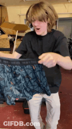 A Man In A Black Shirt Is Holding A Pair Of Underwear That Says Pair Of Twelve GIF
