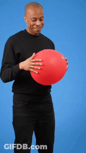 A Man In A Black Shirt Is Holding A Red Balloon In His Hands GIF