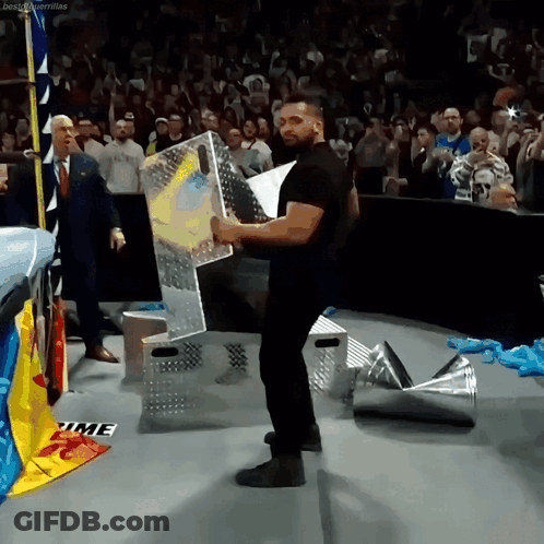 A Man In A Black Shirt Is Holding A Sign That Says Time On The Floor GIF
