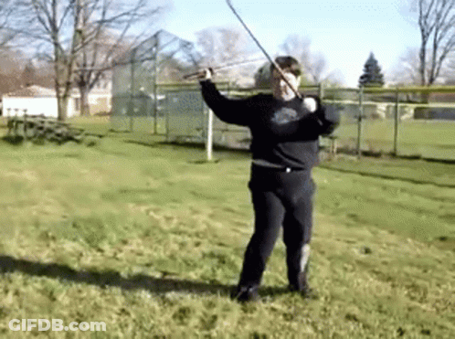 A Man In A Black Shirt Is Holding A Sword In A Field GIF