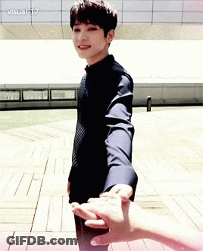 A Man In A Black Shirt Is Holding Another Man 'S Hand While Standing On A Wooden Floor .. GIF