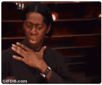 A Man In A Black Shirt Is Holding His Chest With His Hands . GIF