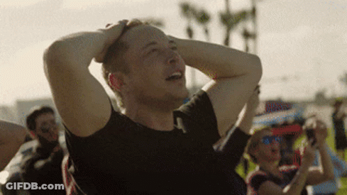 A Man In A Black Shirt Is Holding His Head In His Hands GIF