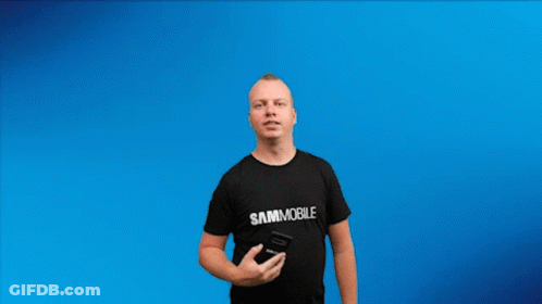 A Man In A Black Shirt Is Holding Up An Android 10 Phone GIF