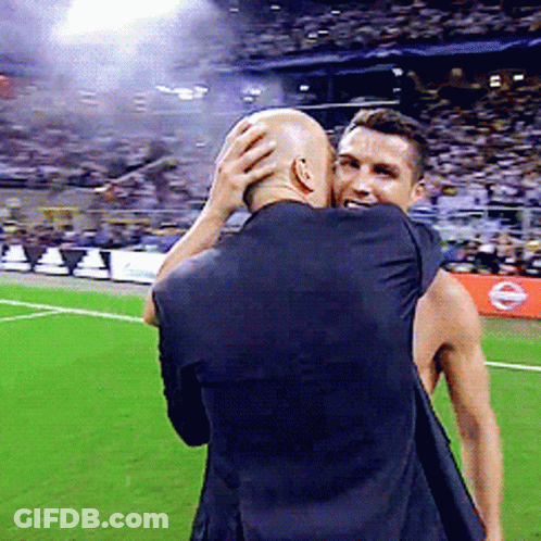 A Man In A Black Shirt Is Hugging Another Man On A Field GIF