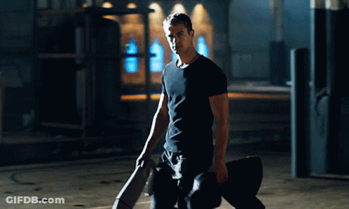 A Man In A Black Shirt Is Kneeling Down Holding A Skateboard GIF