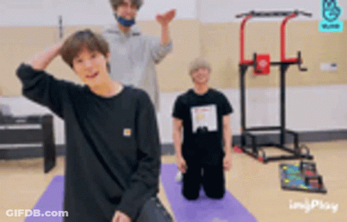 A Man In A Black Shirt Is Kneeling Down On A Yoga Mat GIF