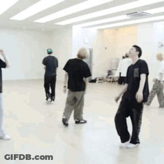 A Man In A Black Shirt Is Kneeling On The Floor In A Dance Studio GIF