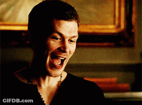 A Man In A Black Shirt Is Laughing With His Mouth Wide Open GIF