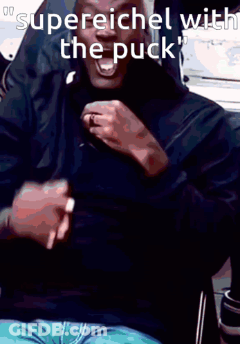 A Man In A Black Shirt Is Laughing With The Words Supereichel With The Puck Below Him GIF