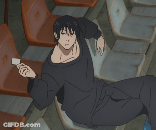A Man In A Black Shirt Is Laying On A Chair Holding A Card GIF