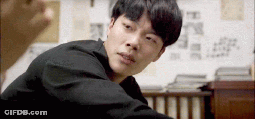 A Man In A Black Shirt Is Looking At The Camera With A Serious Look On His Face GIF