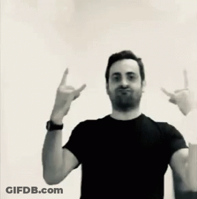 A Man In A Black Shirt Is Making A Devil Horns Sign GIF