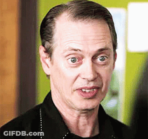 A Man In A Black Shirt Is Making A Funny Face And Looking At The Camera . GIF
