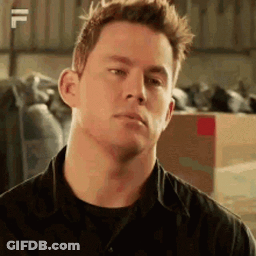 A Man In A Black Shirt Is Making A Funny Face In A Warehouse . GIF
