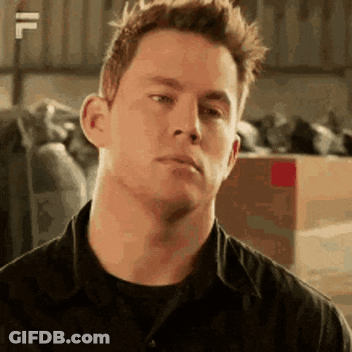 A Man In A Black Shirt Is Making A Funny Face In A Warehouse . GIF
