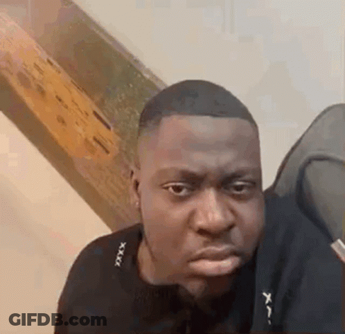 A Man In A Black Shirt Is Making A Funny Face While Looking At The Camera . GIF