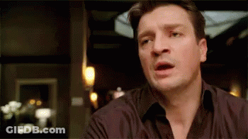 A Man In A Black Shirt Is Making A Funny Face While Sitting At A Table . GIF