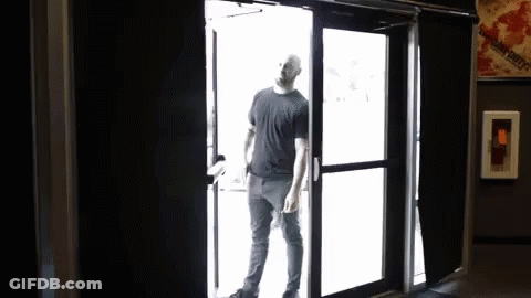 A Man In A Black Shirt Is Opening A Door GIF