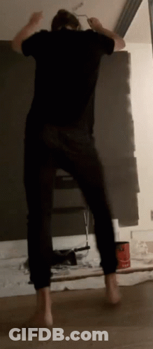 A Man In A Black Shirt Is Painting A Wall With A Brush GIF