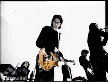 A Man In A Black Shirt Is Playing A Guitar In A Black And White Photo GIF