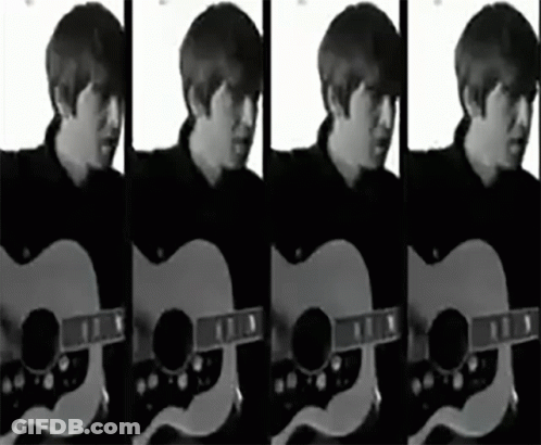 A Man In A Black Shirt Is Playing An Acoustic Guitar In A Black And White Photo GIF