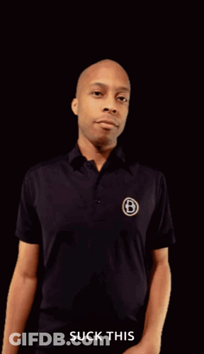 A Man In A Black Shirt Is Pointing His Fist At The Camera With The Words " Suck This " Underneath Him GIF
