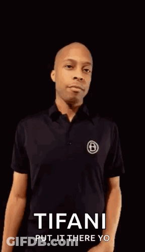 A Man In A Black Shirt Is Pointing His Fist At The Camera With The Words Tifani Put It There Yo On The Bottom . GIF