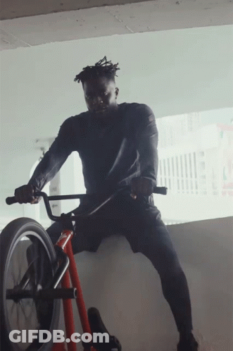 A Man In A Black Shirt Is Riding A Bike GIF