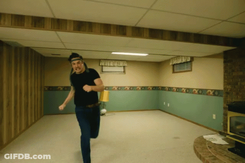 A Man In A Black Shirt Is Running In A Room GIF