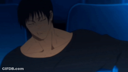 A Man In A Black Shirt Is Sitting In A Dark Room With His Arm Outstretched GIF