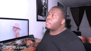 A Man In A Black Shirt Is Sitting In Front Of A Computer GIF