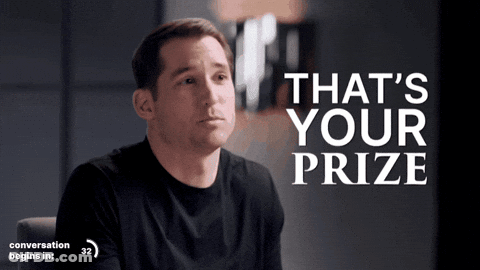 A Man In A Black Shirt Is Sitting In Front Of A Sign That Says That 'S Your Prize GIF