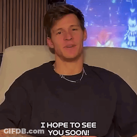 A Man In A Black Shirt Is Sitting On A Couch And Saying " I Hope To See You Soon " GIF