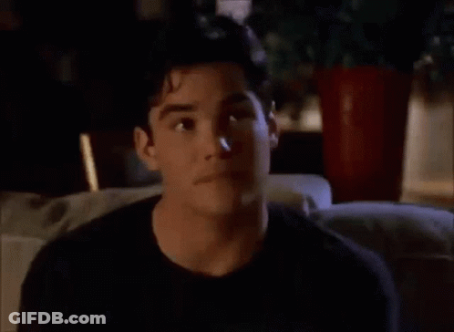 A Man In A Black Shirt Is Sitting On A Couch Looking At Something GIF